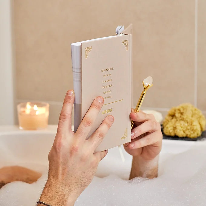 Mann in Badewanne schreibt in sein 5 Minuten Manifestation Journal