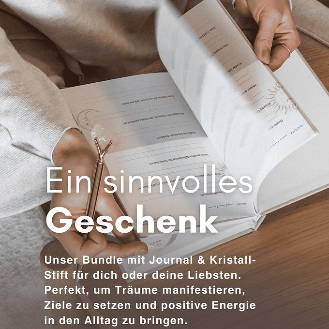 5 Minuten Manifestation Journal und Kristallstift mit einer Frauen Hand auf einem Tisch.