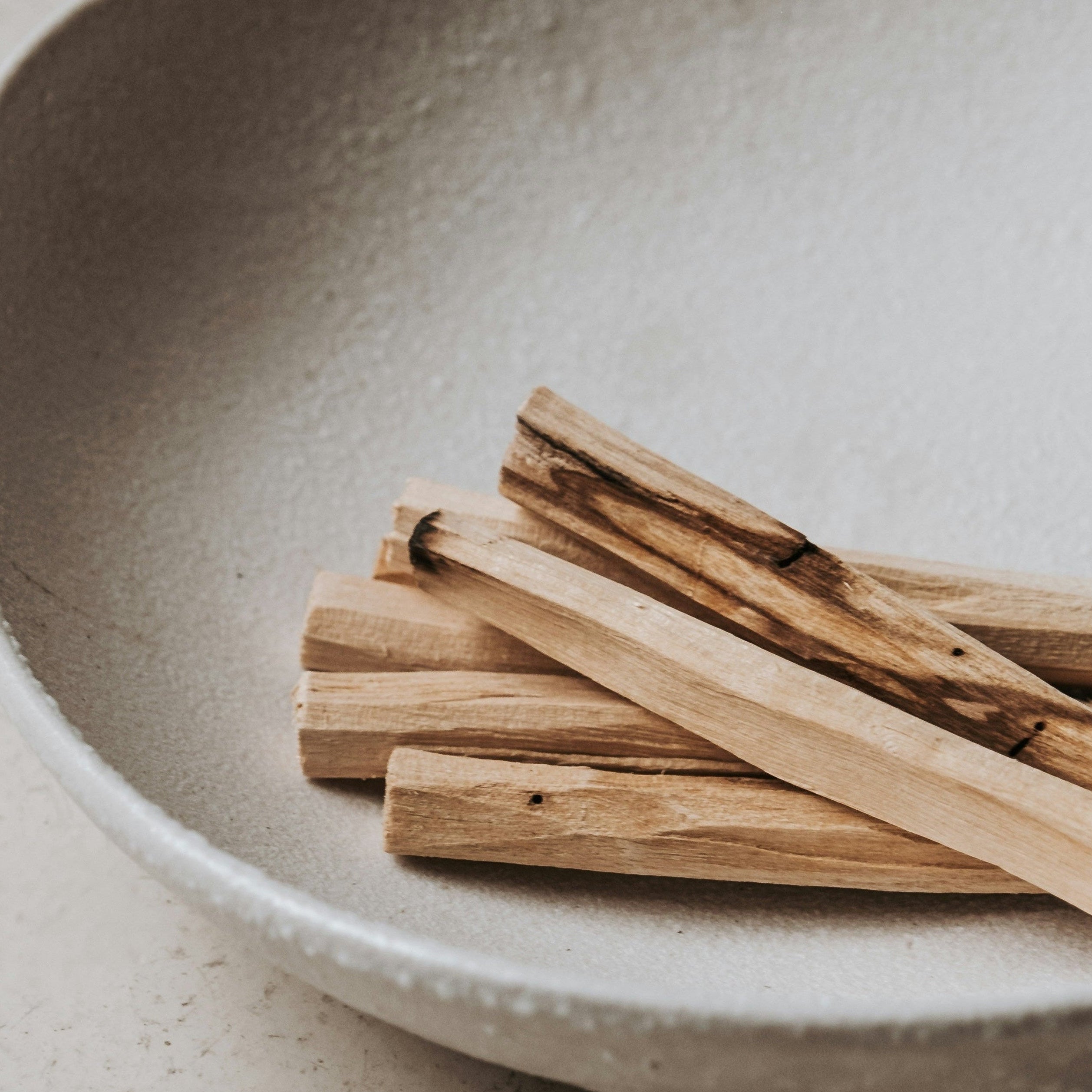 Palo Santo Räucherholz in einer Keramikschale mit Streichhölzern für ein achtsames Räucherritual