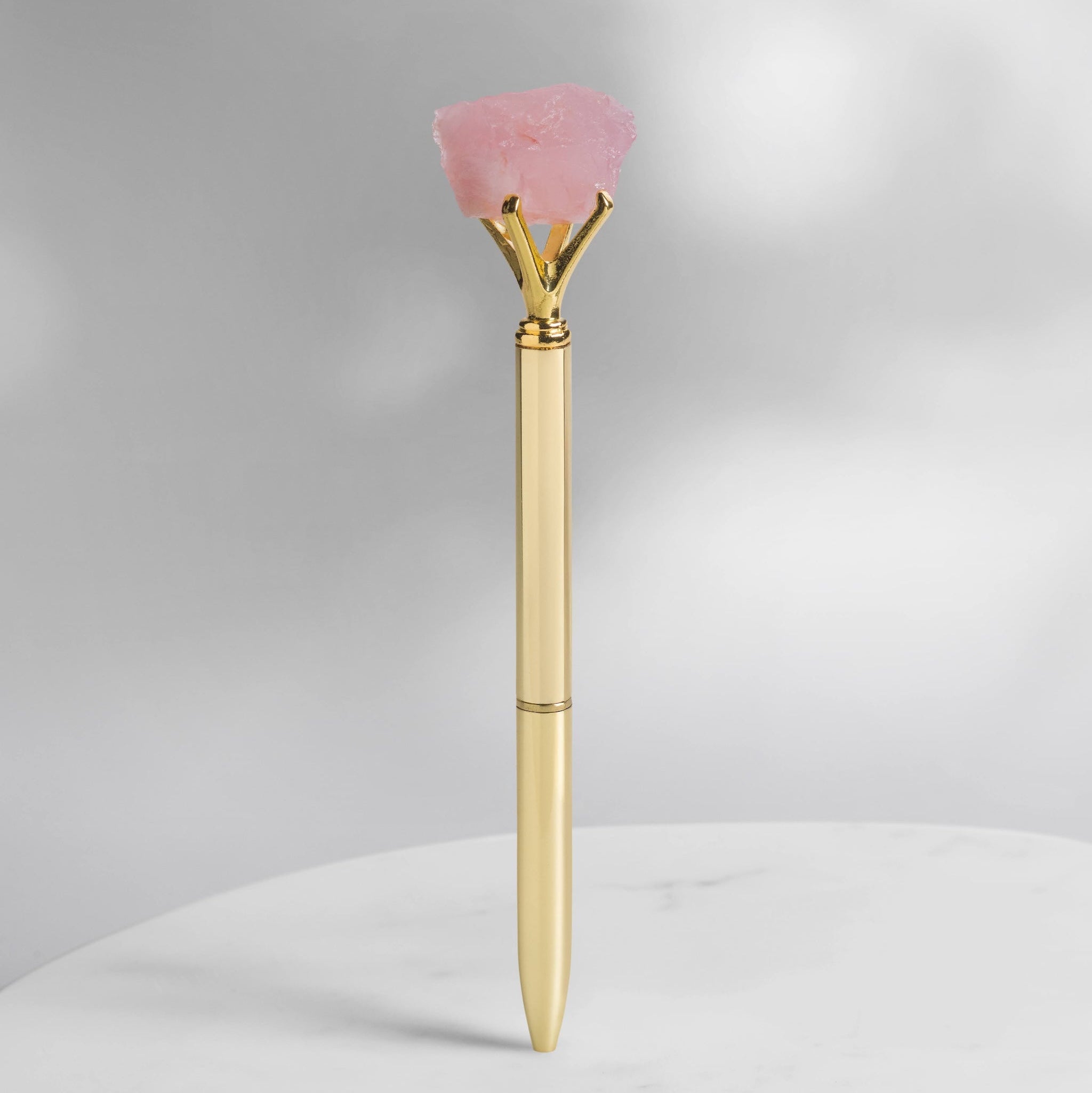 Rosenquarz Kristallstift in Goldoptik mit rohem Rosenquarz, Kristallstift für Selbstliebe, Herzenergie, Journaling und Manifestation auf hellem Hintergrund.