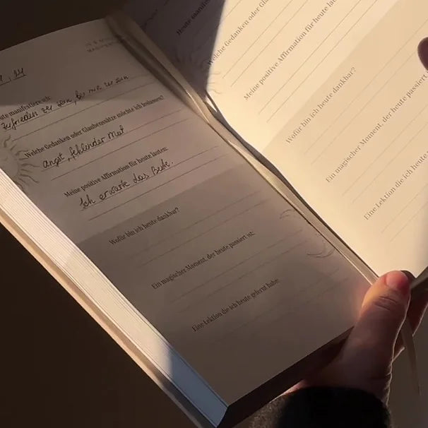 Frau blättert im Raum mit Licht und Schatten in ihrem 5 Min. Manifestation Journal