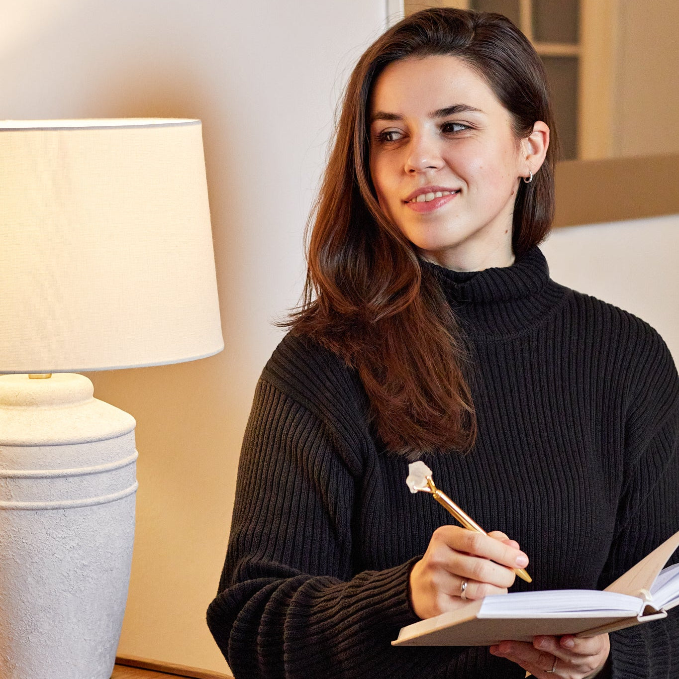 Frau mit braunen Haaren schreibt in ihr 5 Minuten Manifestation Journal mit ihrem Kristall Stift aus Bergkristall.