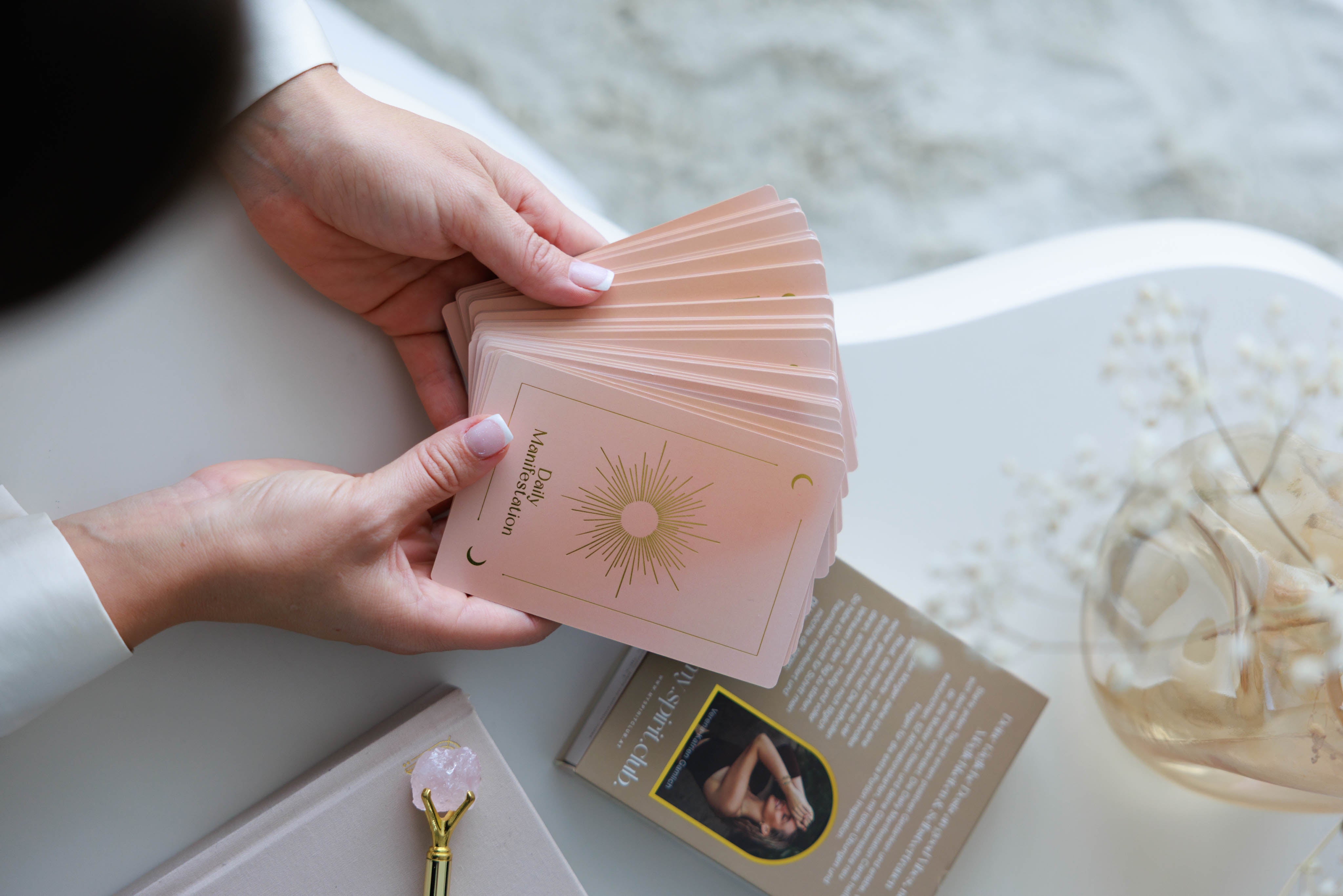 Hände halten Daily Manifestation Karten in zartem Rosé für tägliche Affirmationen und Rituale