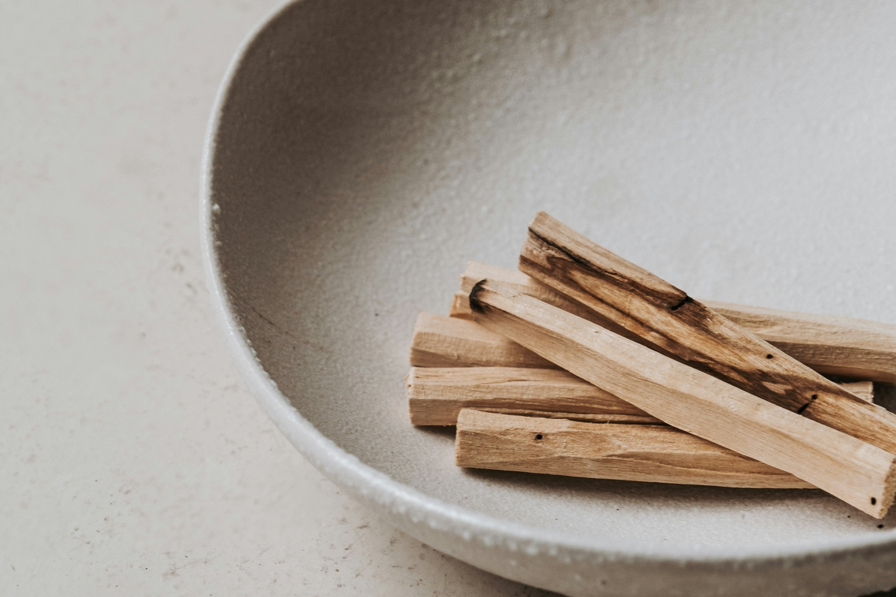 Palo Santo Räucherholz in einer Keramikschale mit Streichhölzern für ein achtsames Räucherritual