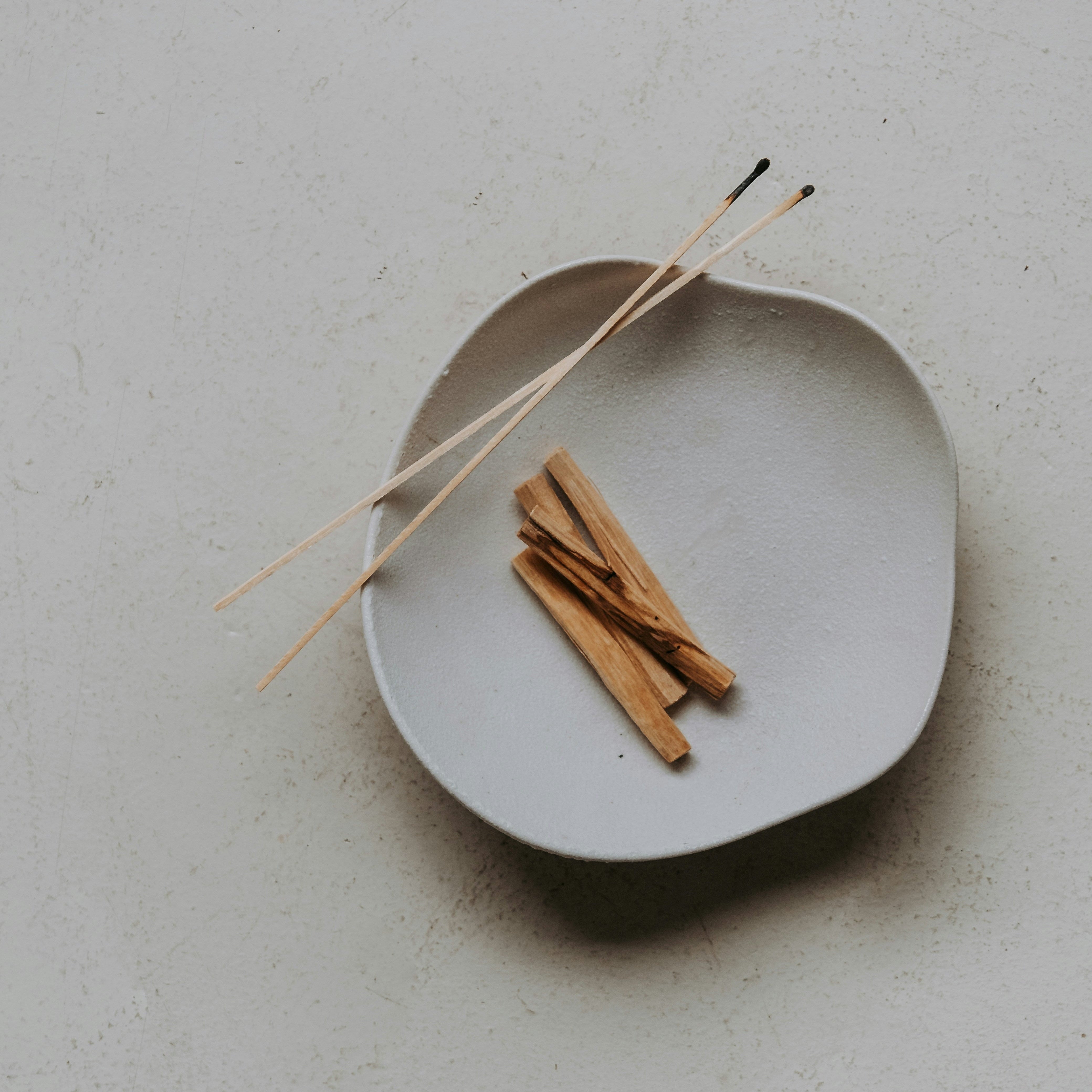 Palo Santo Räucherholz in einer Keramikschale mit Streichhölzern für ein achtsames Räucherritual