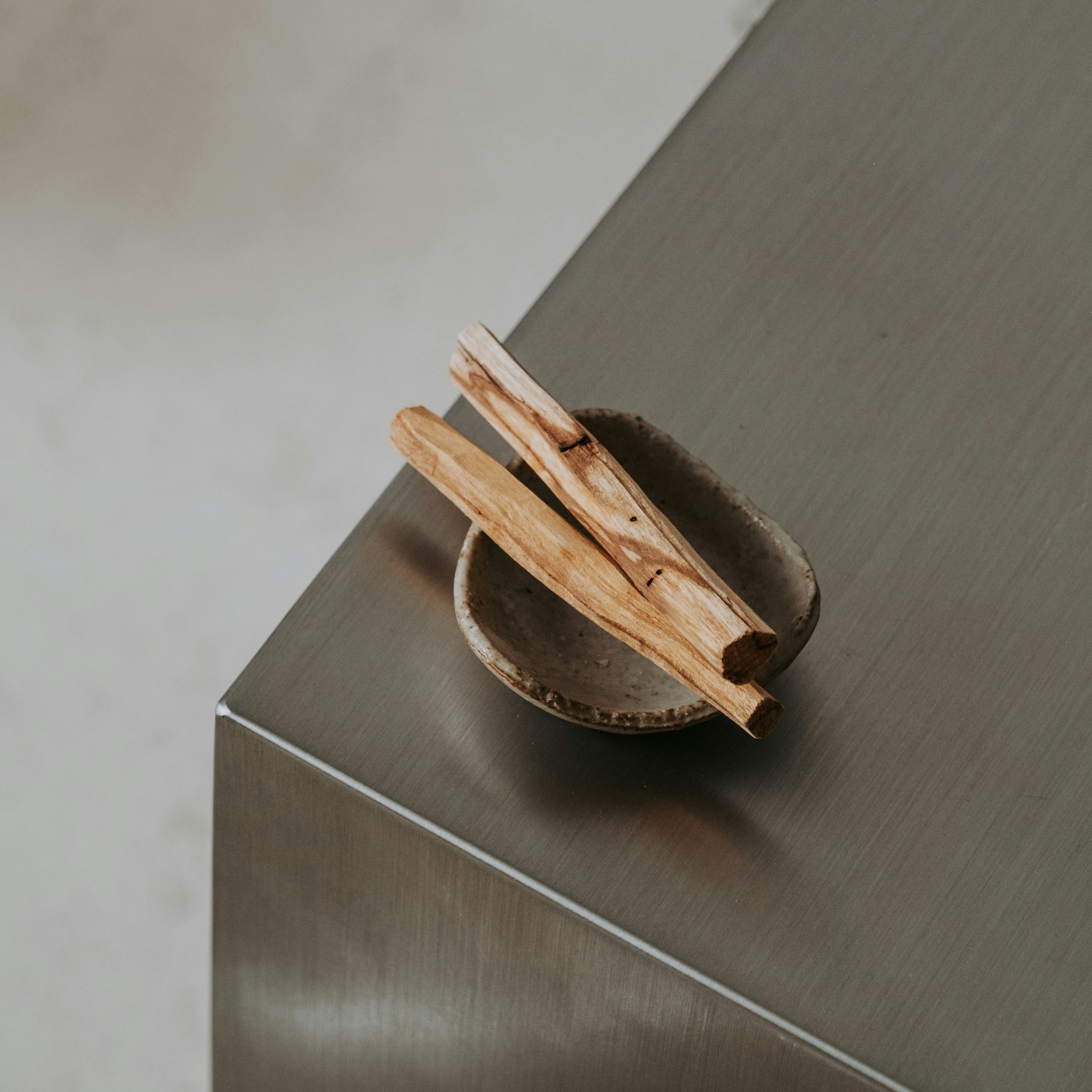 Palo Santo Räucherholz in einer kleinen Schale auf einer minimalistischen Oberfläche