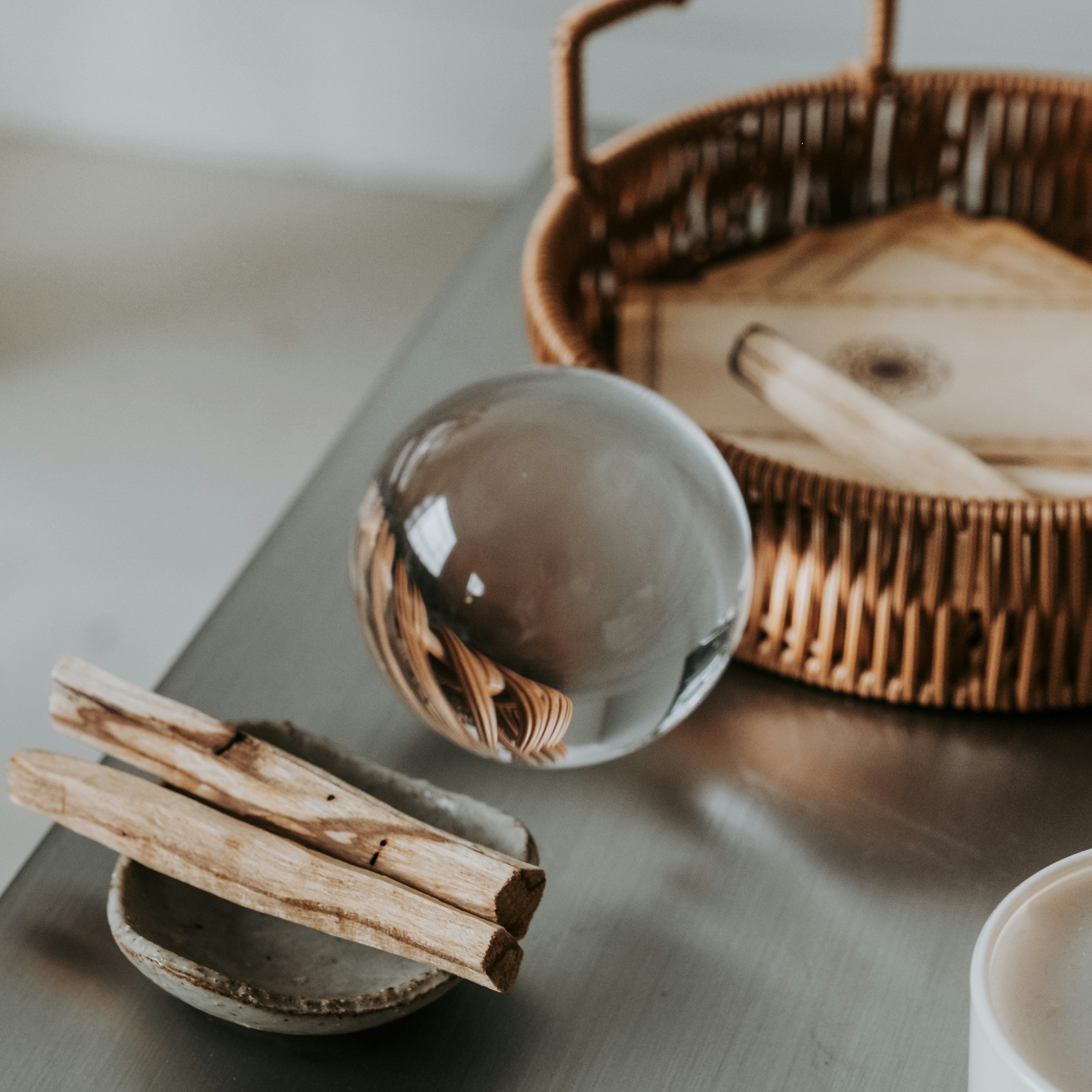 Palo Santo Räucherholz in einer Schale mit Glaskugel und natürlichen Ritualobjekten